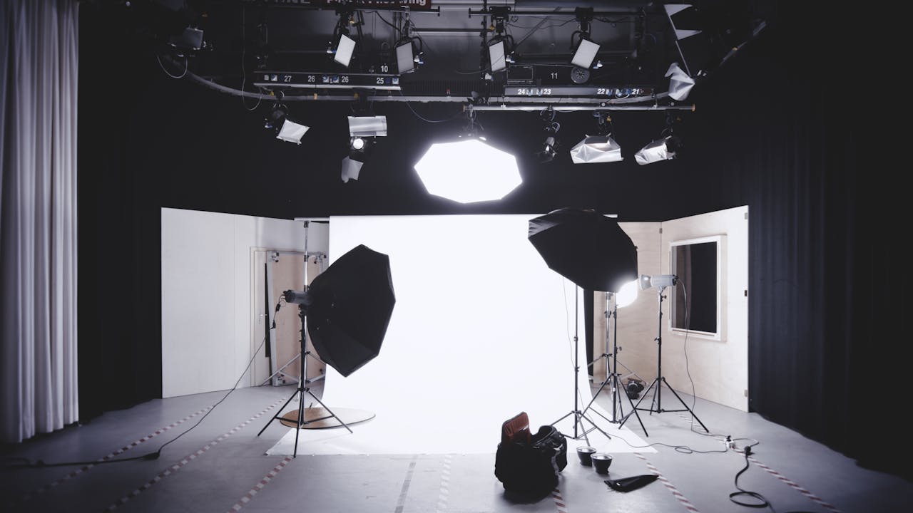 gallery-04 A well-equipped photography studio featuring lights, softboxes, and a white backdrop for professional shoots.