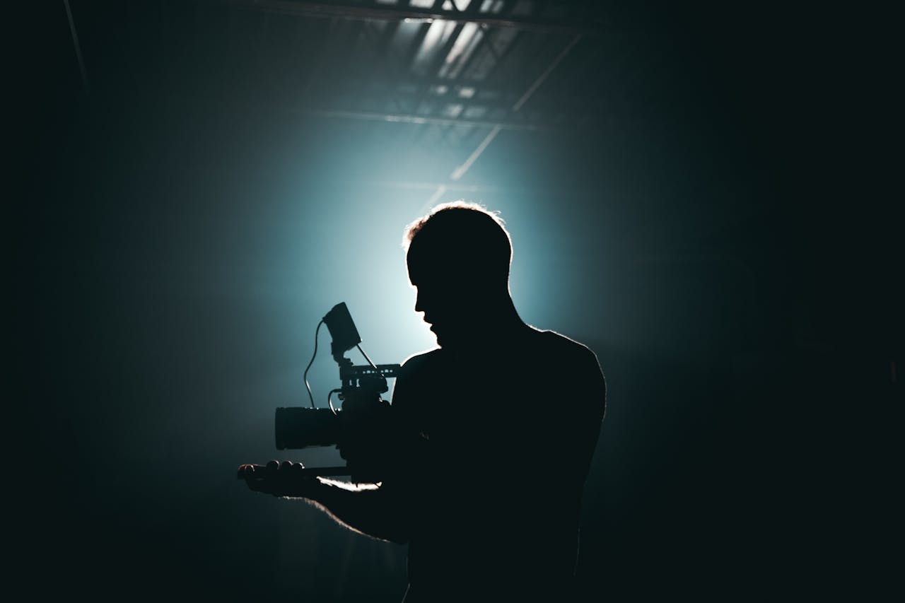 services-03 Silhouette of a cinematographer with camera gear in a dramatic, low light setting.