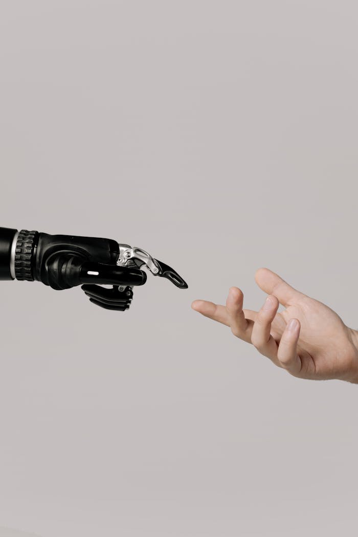portfolio-01 A human hand reaching to touch a bionic prosthetic hand on a white background.